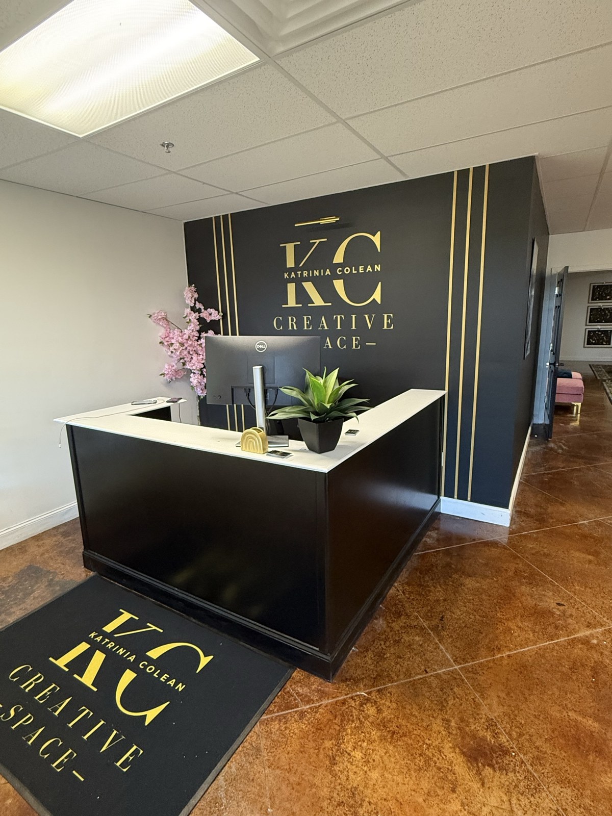 KC Creative Space — the signature black and gold reception desk with the Katrinia Colean logo on the wall